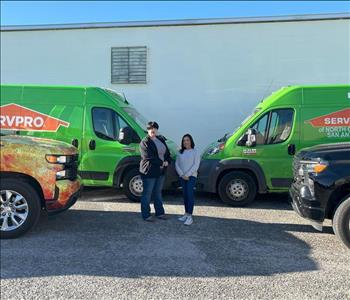 Two women standing in front of SERVPRO vehicles