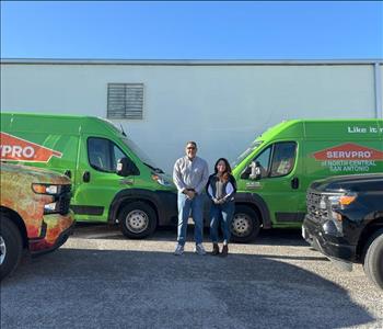 Man and Woman Standing in front of SERVPRO trucks